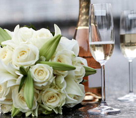 A wedding bouquet next to a bottle of champagne and two flutes