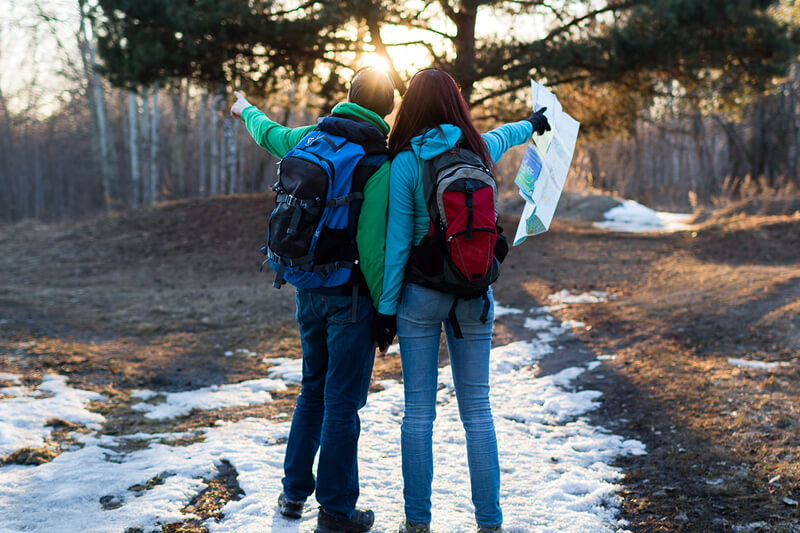 COuple with backpacks hiking on snow covered ground in Santa Fe