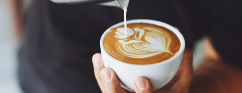 Barista pouring cream into cup for a decorative latte