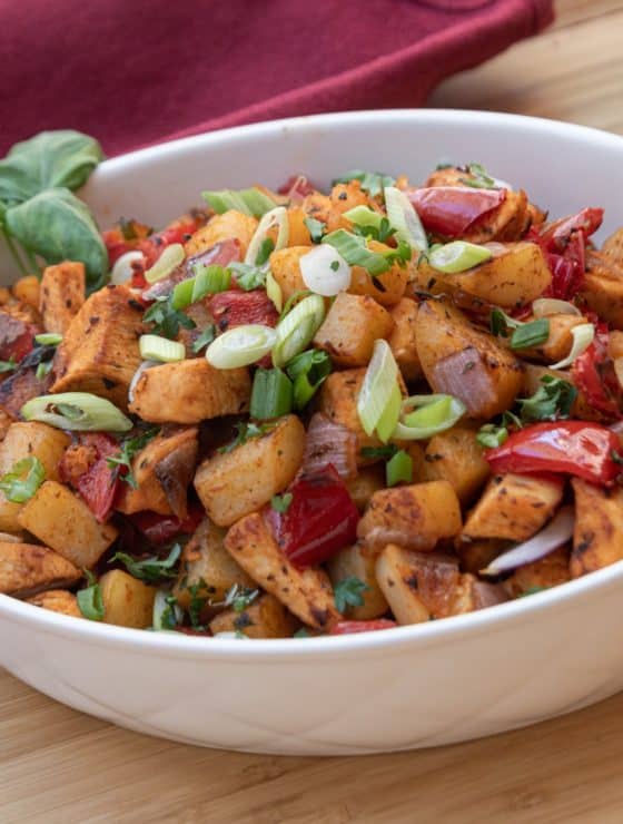 White serving bowl of Sweet Basil Chicken Hash including diced chicken, potatoes, red peppers, red onions, green onions, parsley and sweet basil