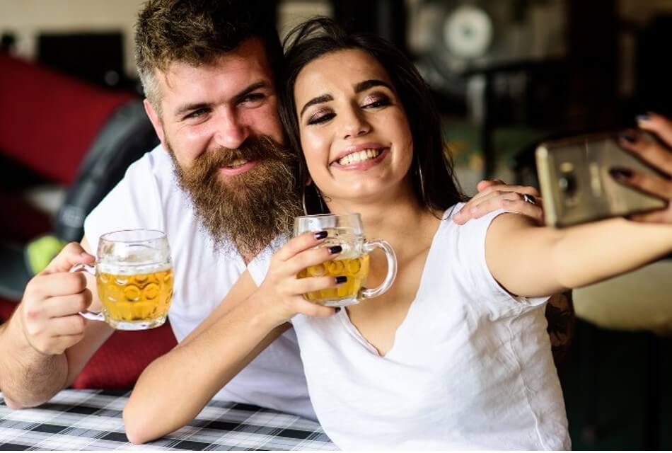 Young couple enjoy a beverage while taking a selfie.