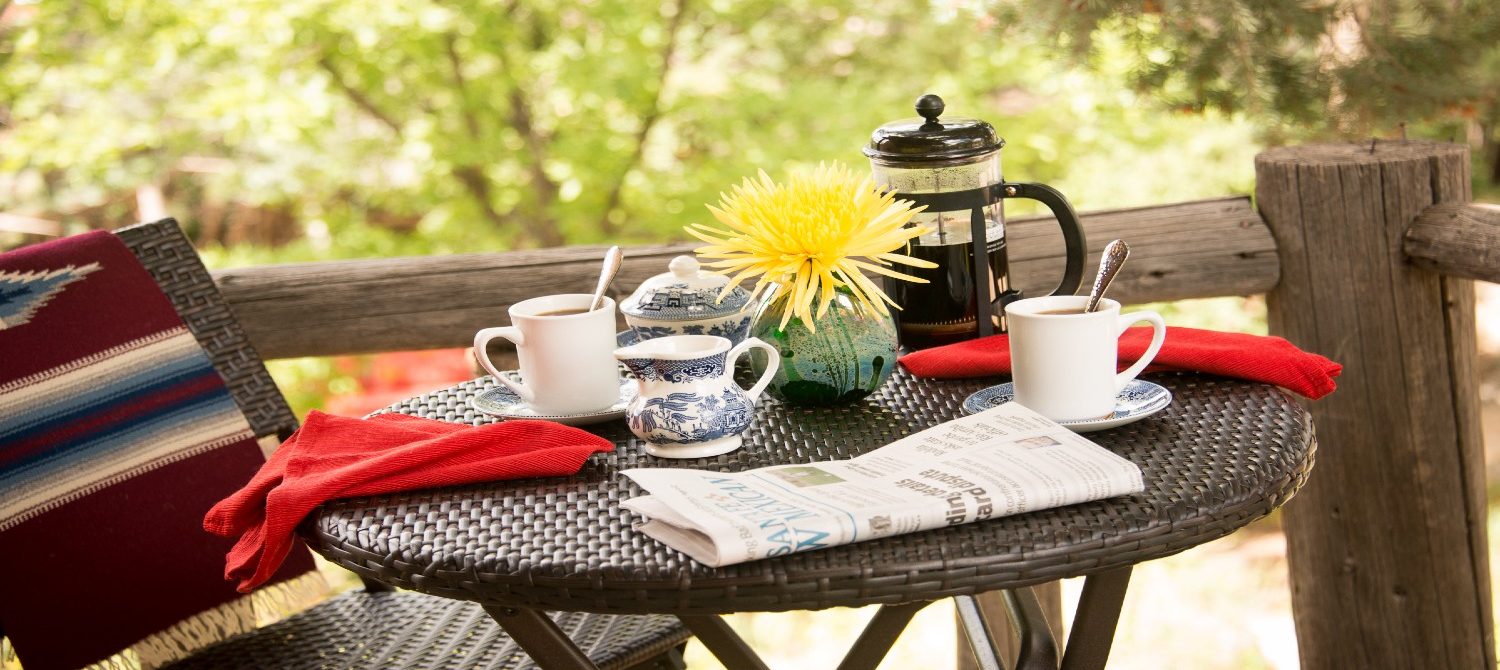 cafe table, chairs, coffee and baked goods on balcony