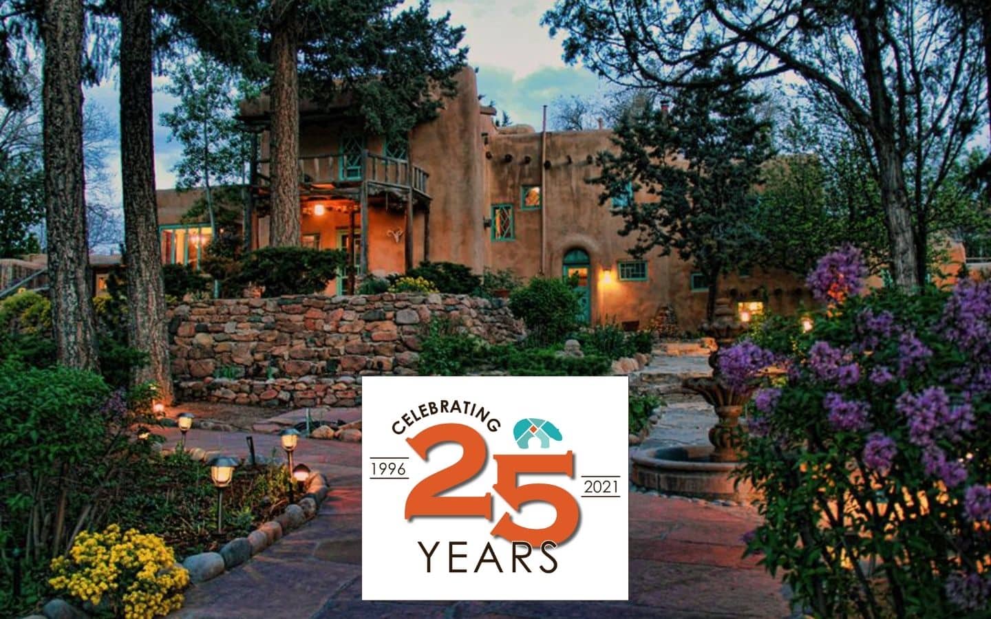 Exterior view of the Inn at dusk in the spring with twinkling lights and beautiful flowing plants and trees.