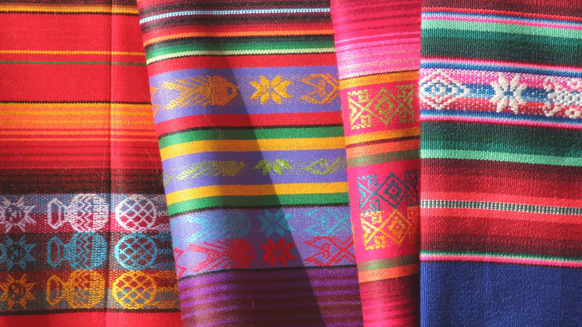 Close up view of woven Native American blankets with red, orange, green, and blue designs
