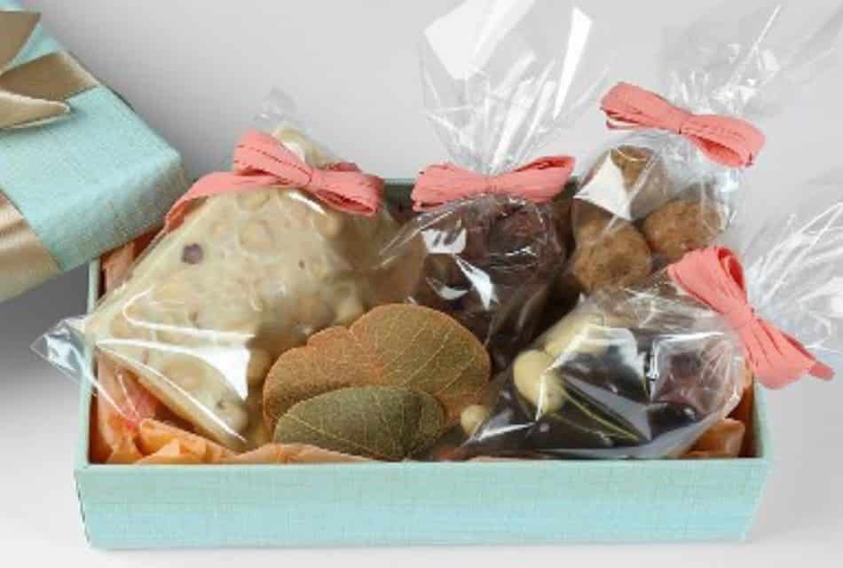 Pale turquoise cloth box filled with candies wrapped in cellophane with peach ribbons.
