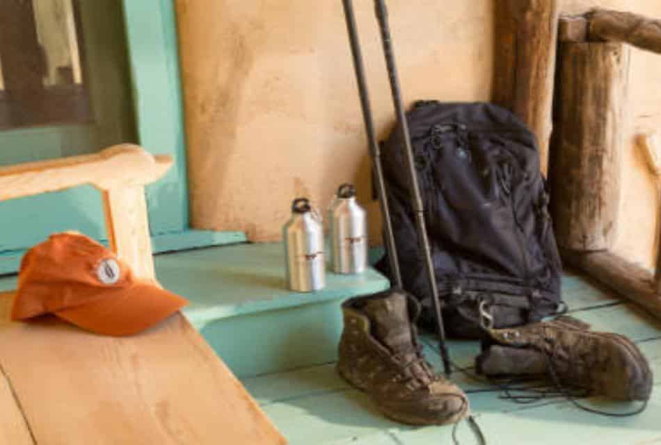 Hiking gear set on bench and steps of adobe house with turquoise wooden porch.