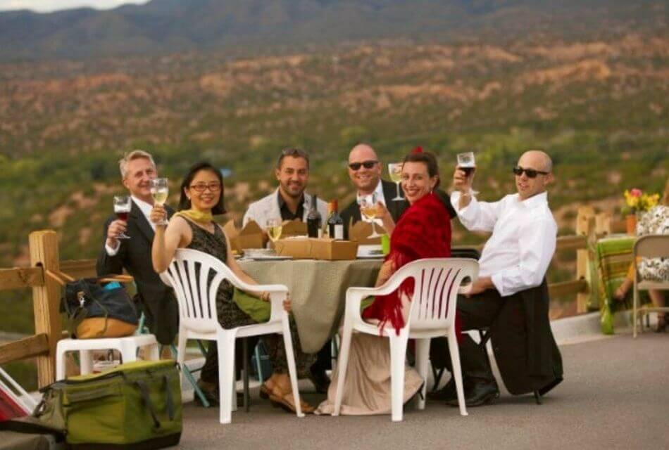 Group of well-dressed people raising glasses at an outdoor table