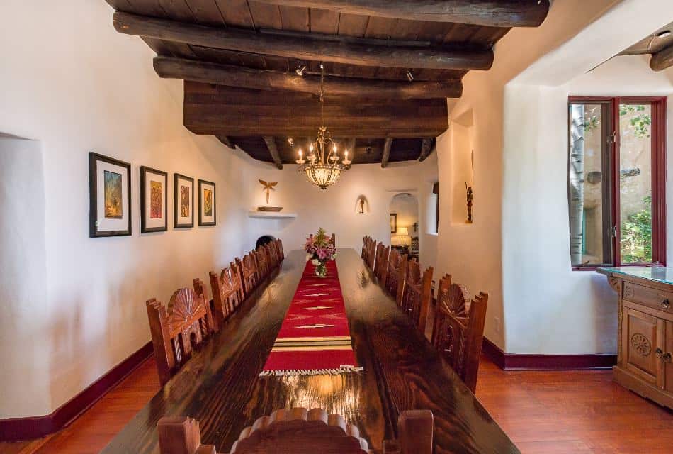 Long Santa Fe-style wooden table in dining room with 14 chairs under a Southwestern chandelier.