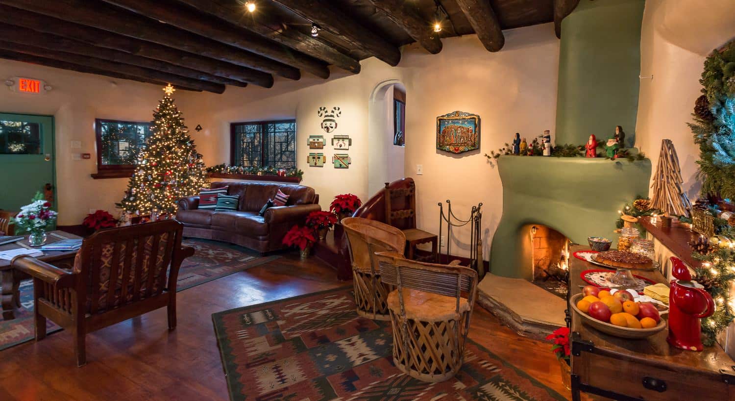 Large gathering room with hardwood floors, cream walls, leather sofa, sitting area, green painted fireplace, and Christmas tree