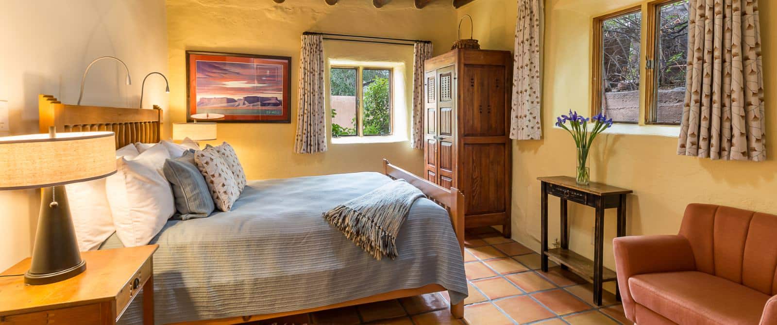 Southwestern-style bedroom with queen bed, wooden armoire and Saltillo tile floor.