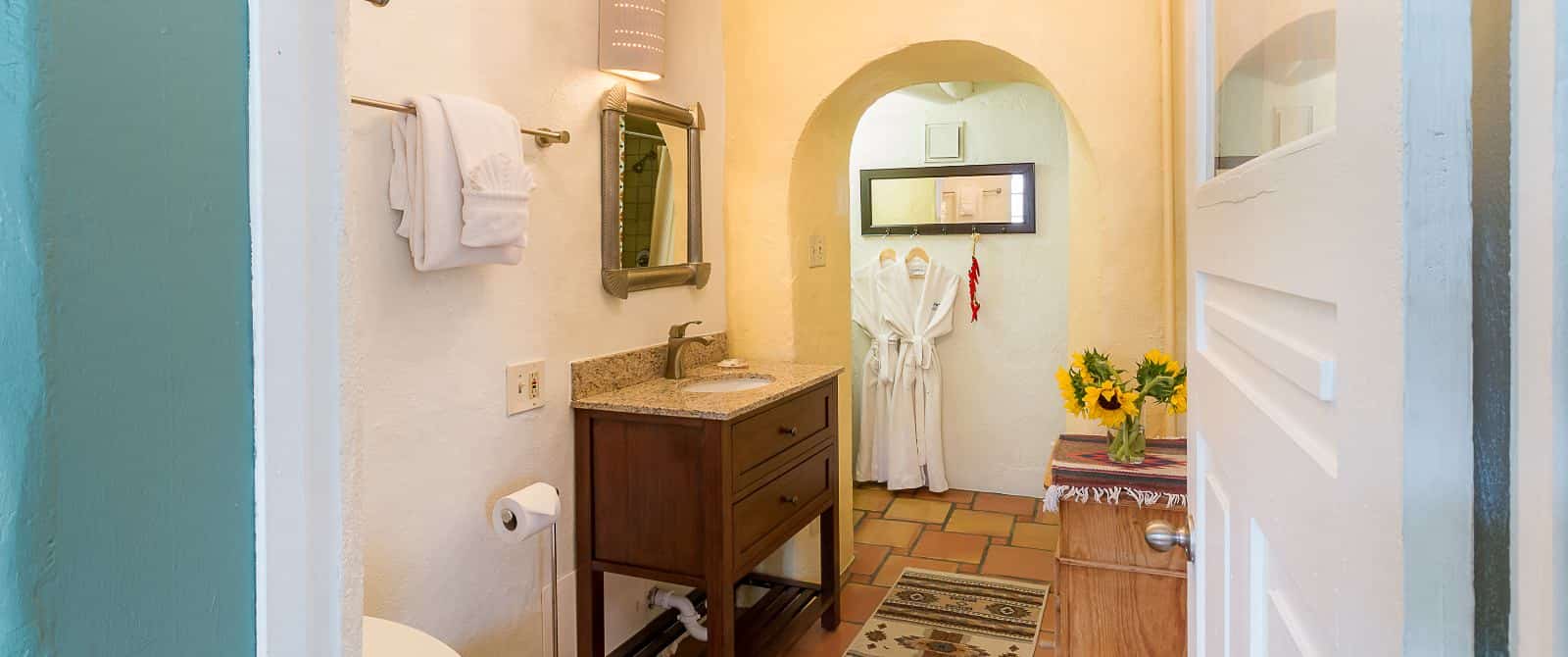 Foyer to bathroom with wooden sink vanity and dresser, wooden mirror and tile floor.