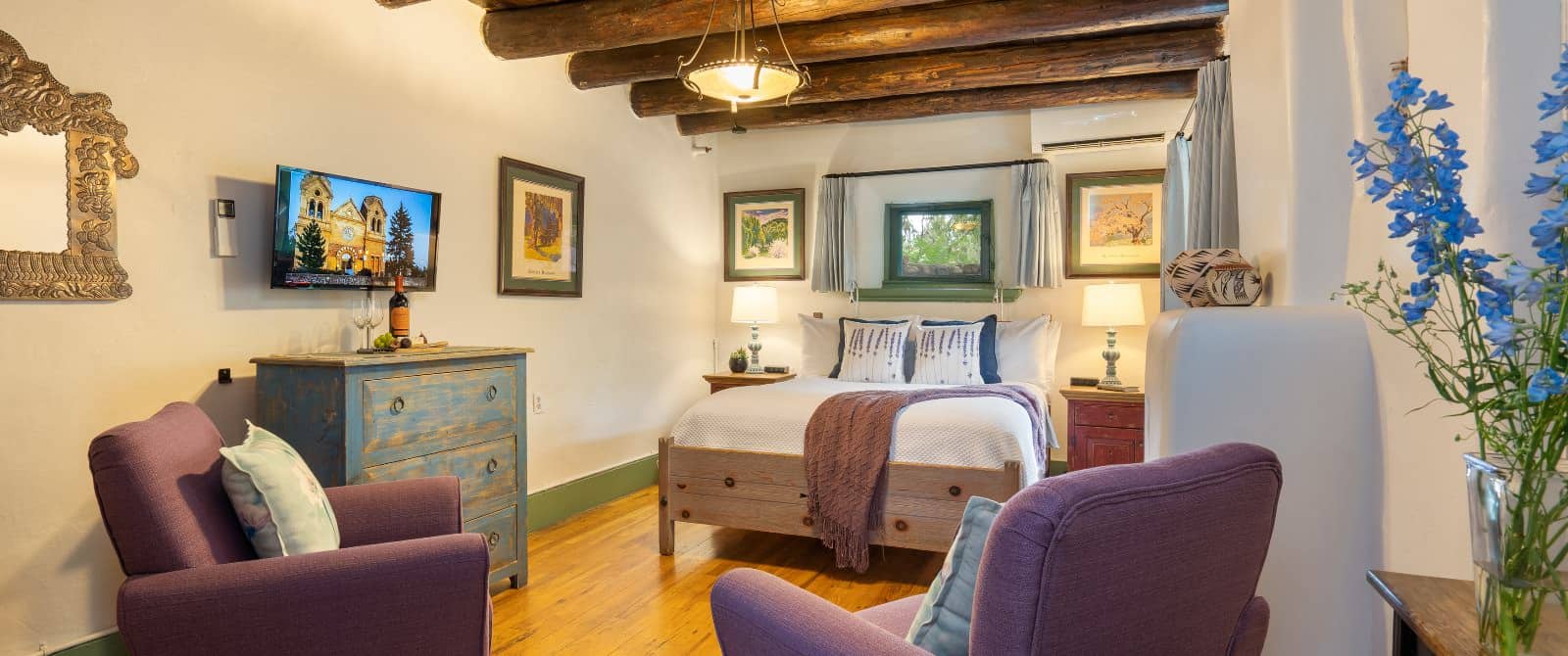 Cozy timber beam bedroom with southwest-style furniture, wood floor and two mauve armchairs.