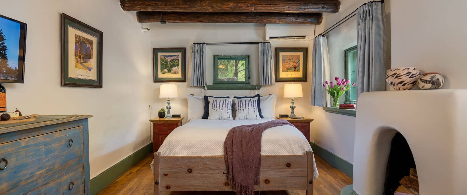 Cozy timber beam bedroom with southwest-style furniture, wood floor and pueblo-style fireplace.