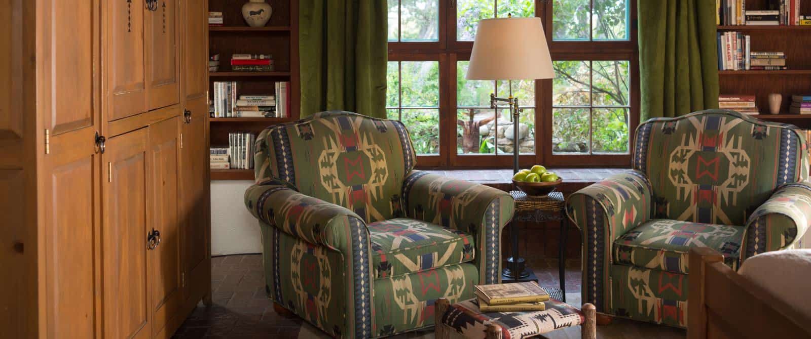Two armchairs upholstered in Southwestern fabric in front of a wooden-framed window and built-in bookcases.
