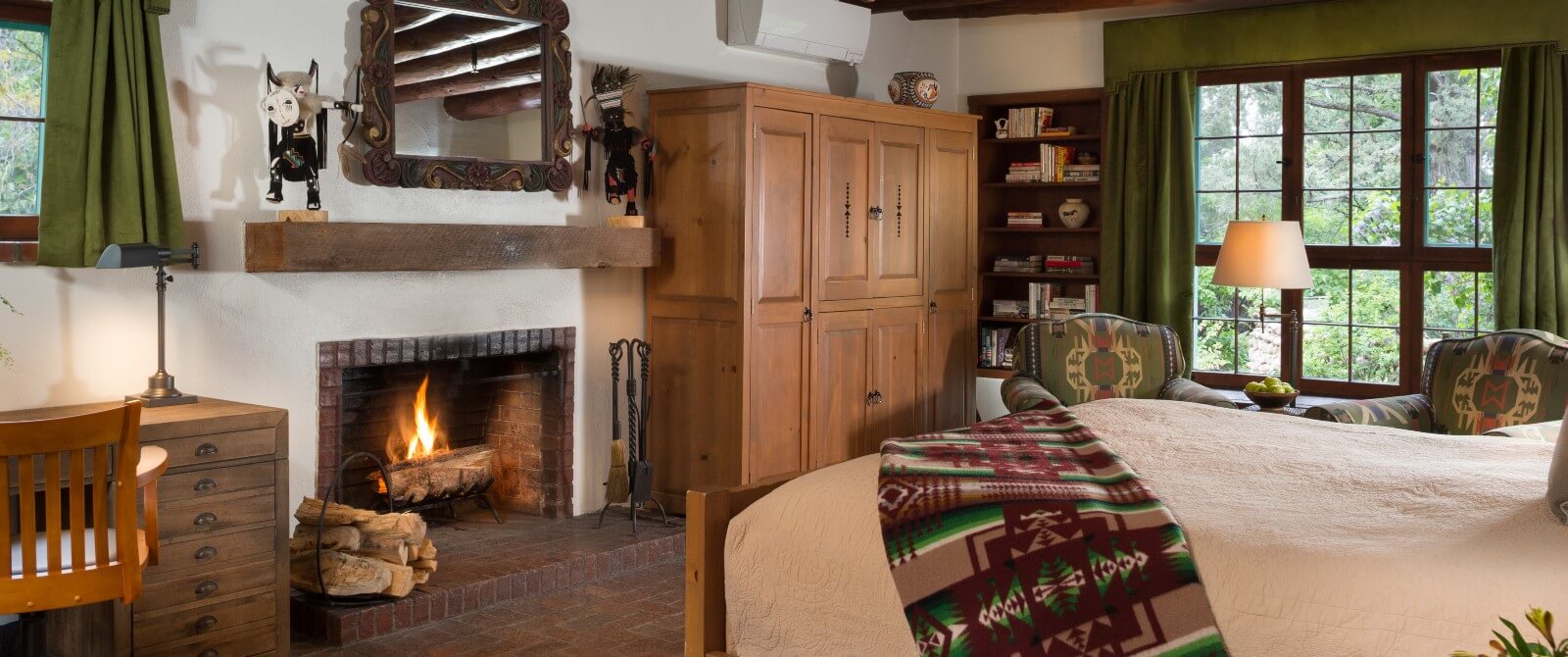 King sized bed, desk, two reading chairs, large wardrobe, fire burning in wood burning fireplace and windows with garden views