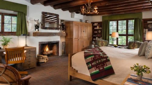 Bedroom with brick floor, timber-beam ceiling, elk-horn chandelier and Native American art decor.