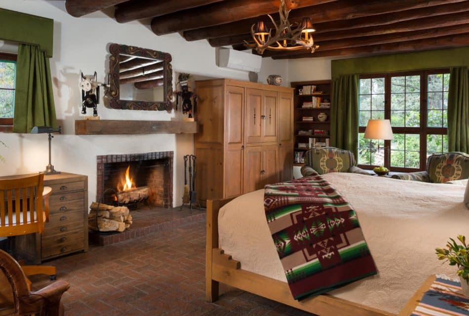 Bedroom with brick floor, timber-beam ceiling, elk-horn chandelier and Native American art decor.