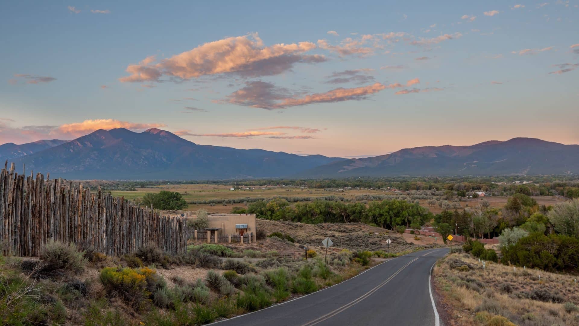 Road through Teos NM surrounded by desert landscape and mountains on the horizon