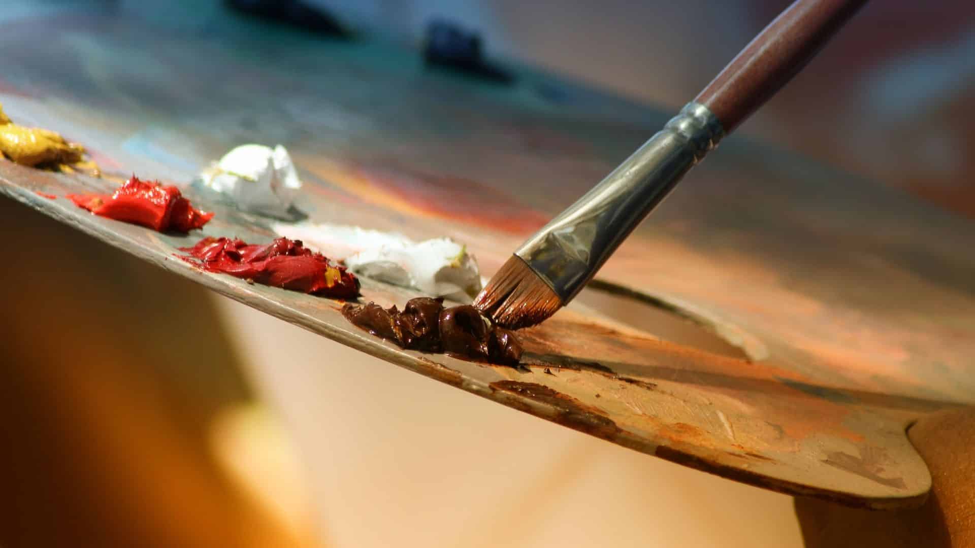 Paint brush dipped into paint on a palette