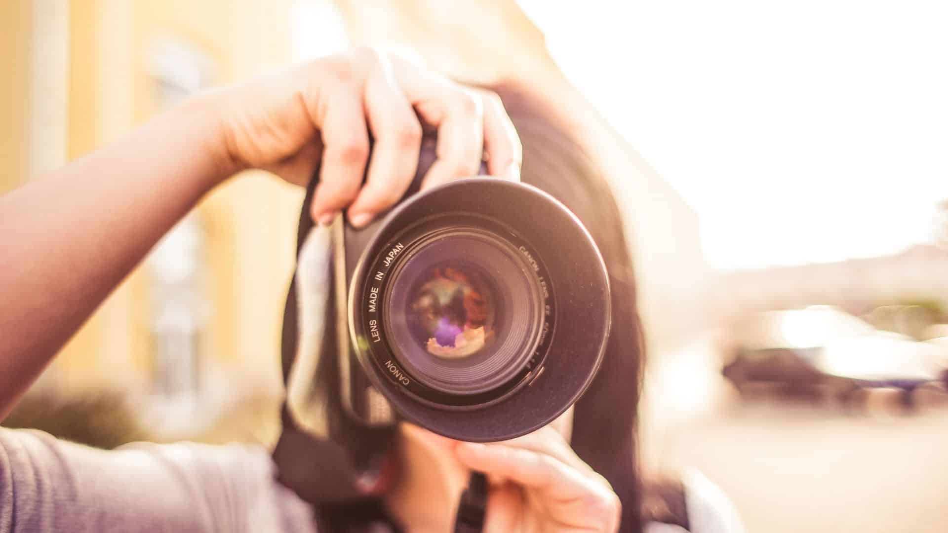 Woman holding a camera in front of her face getting ready to take a picture
