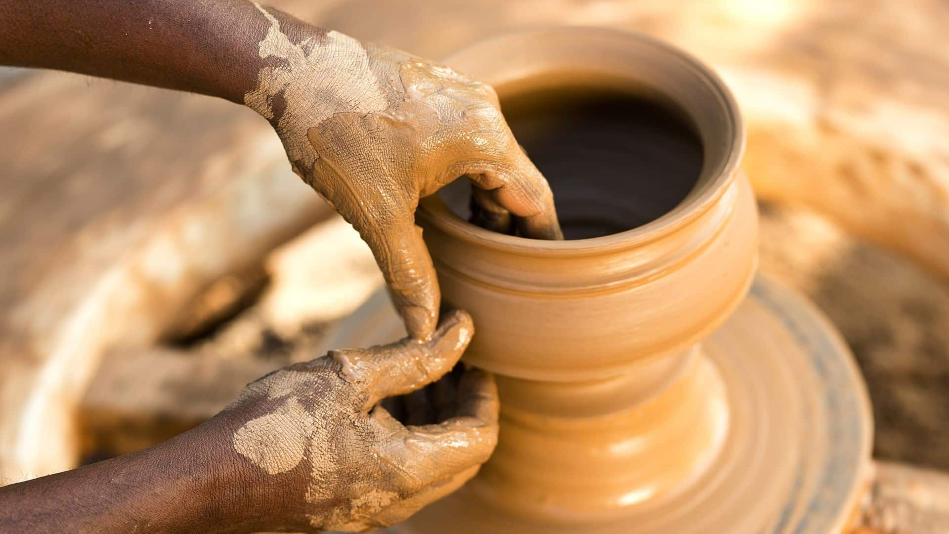 Man making pottery with his hands on a pottery wheel