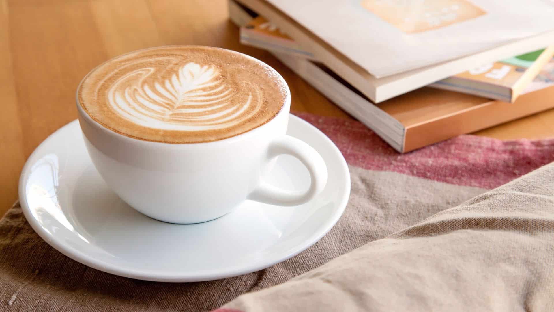 Cappuccino in a cup next to an open book