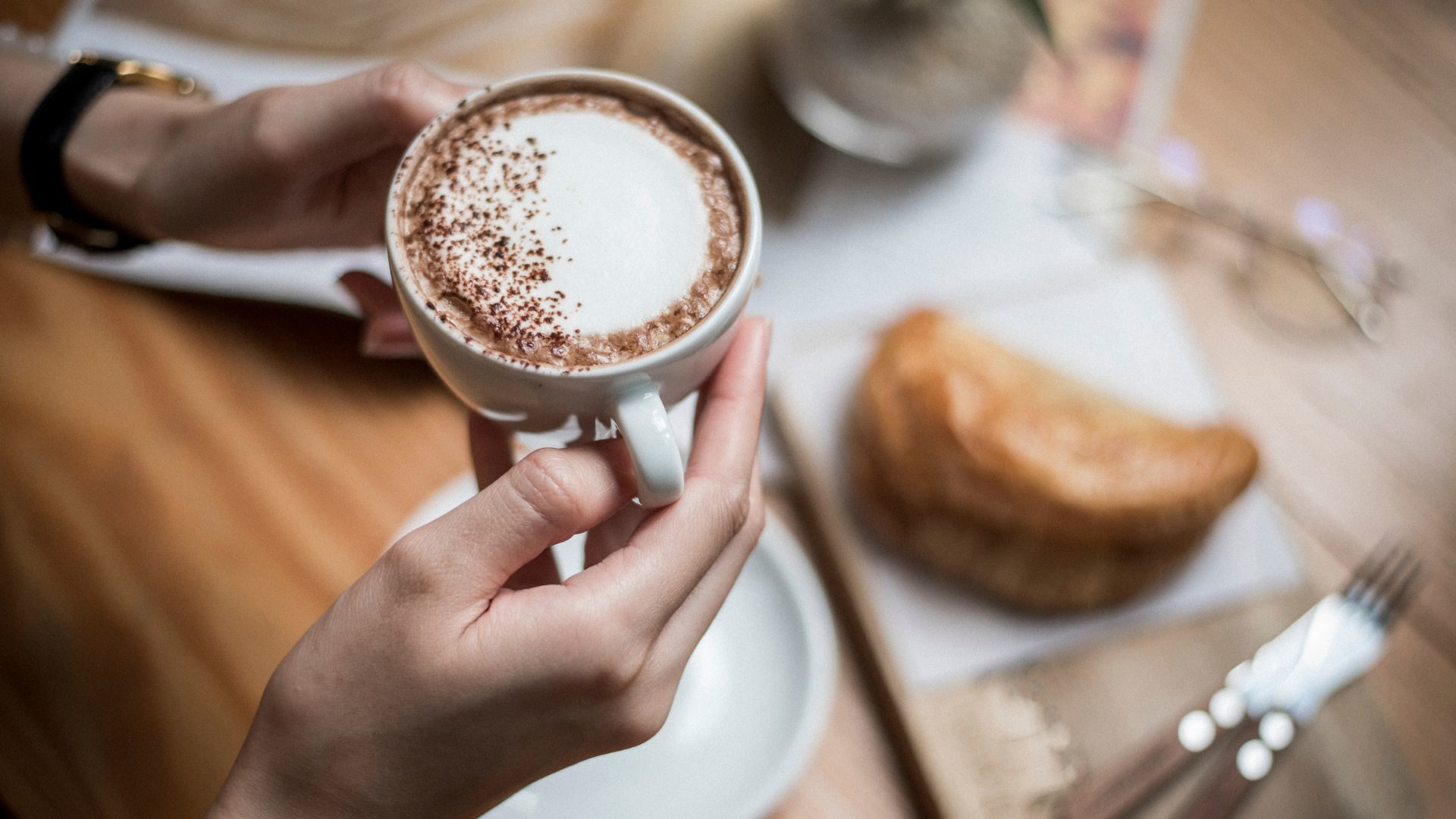 Person holding a cup of latte with sprinkled cinnamon