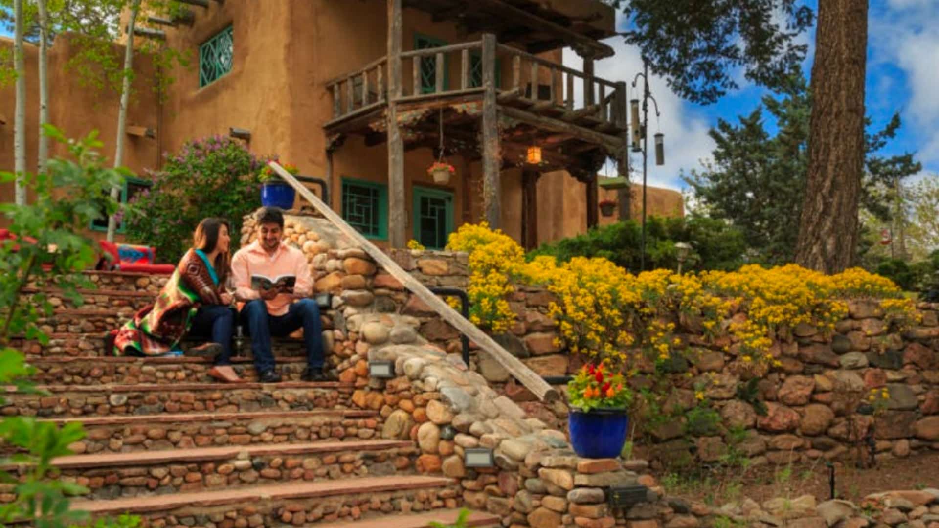 A couple sitting and reading on the steps of Inn of the Turquoise Bear in summertime