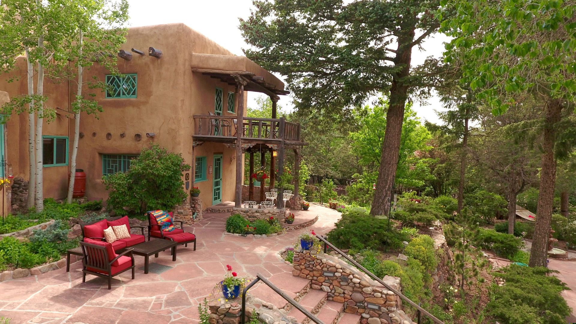 Red flagstone patio at Hermann Hill with comfy chairs and steps down to lush gardens.