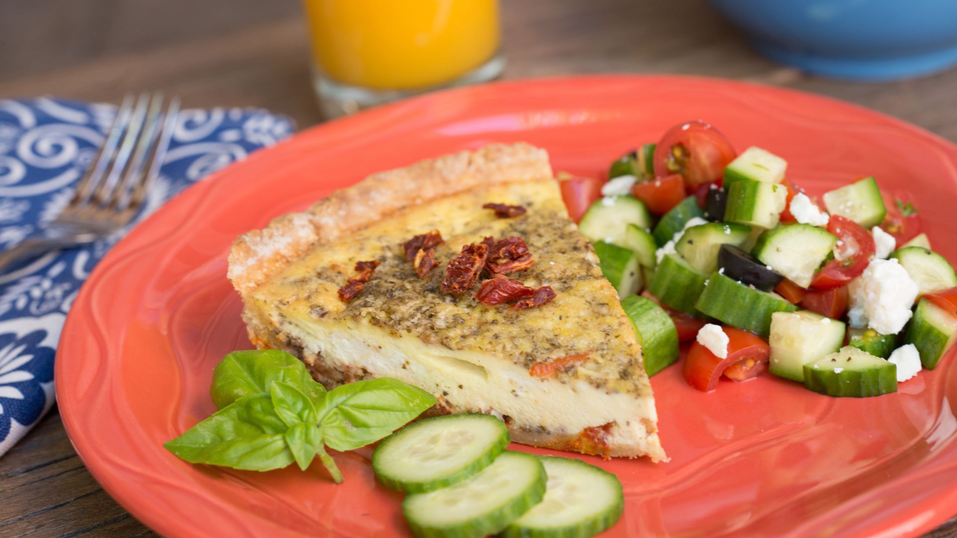Bright orange-red stone plate topped with fresh baked quiche and veggies