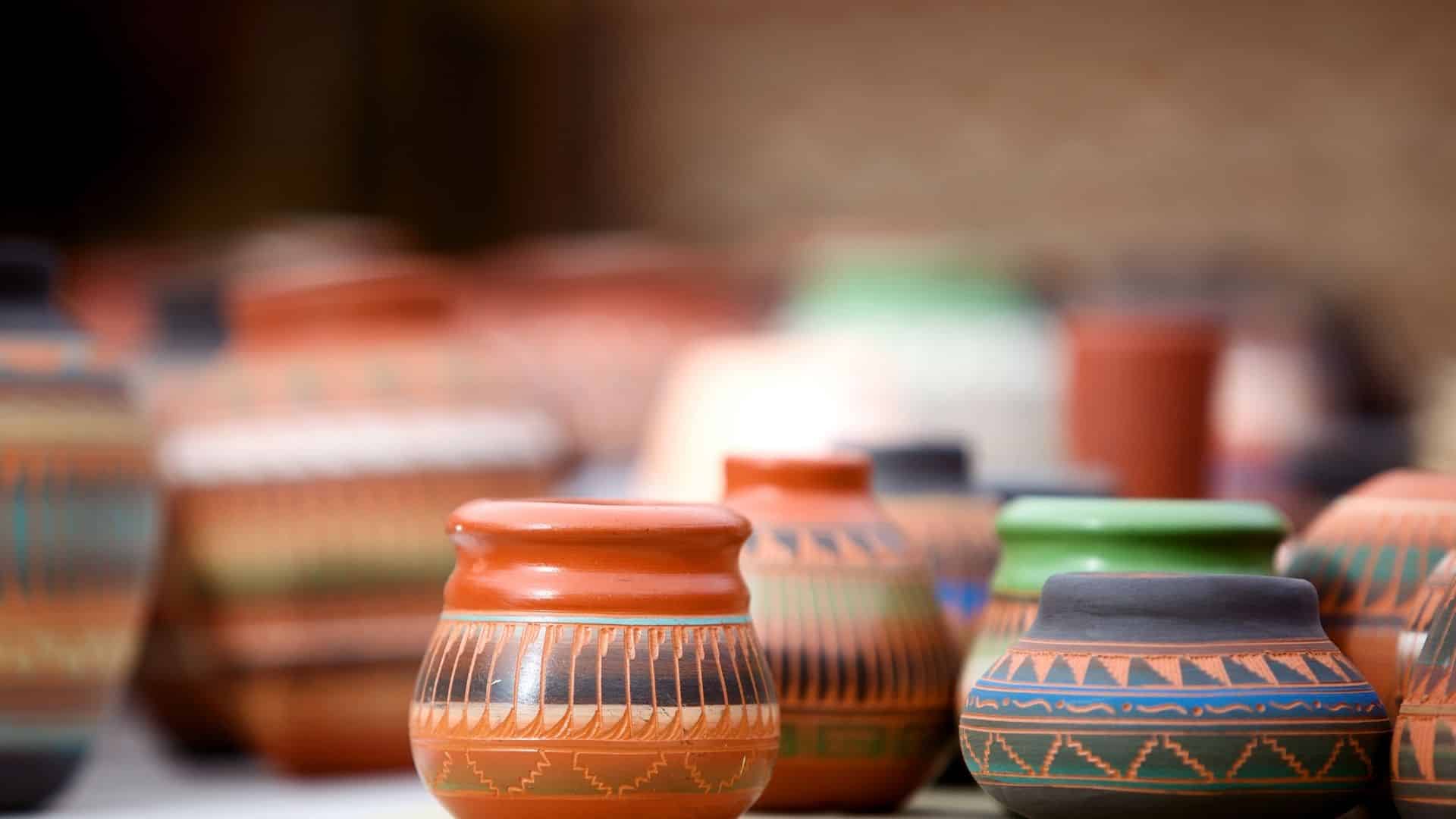 Rows of native american pottery in shades of terra cotta, green, gold and blue