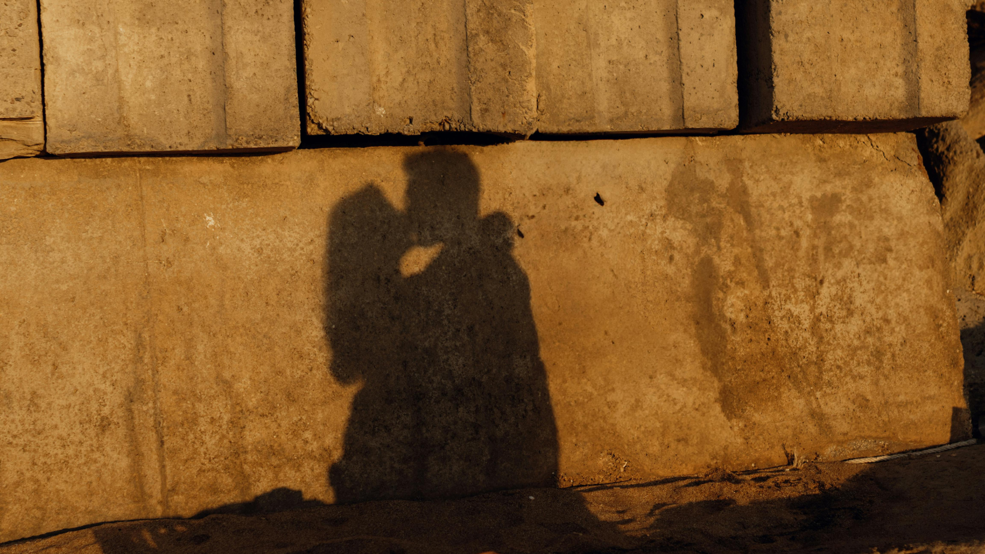 shadow of a couple kissing cast on a sunlit stone wall