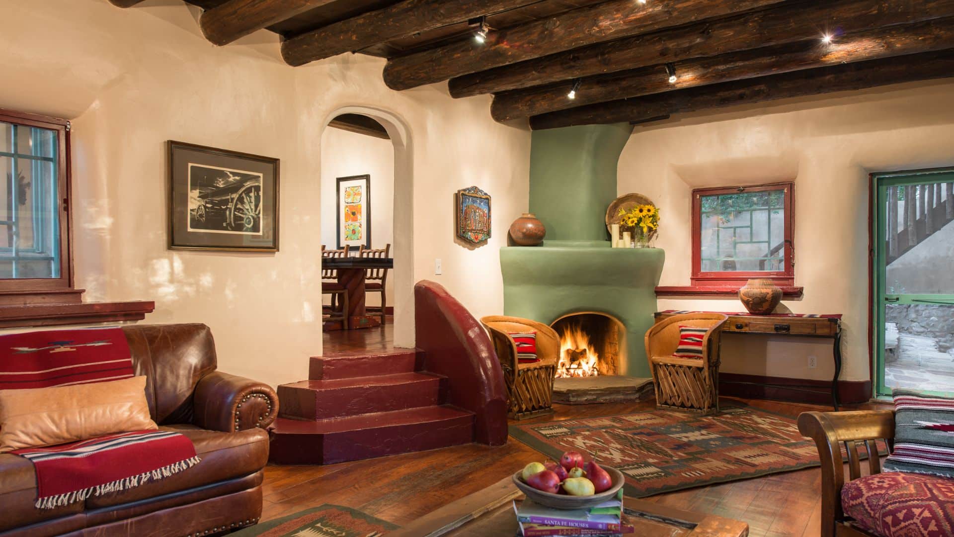 Living room with beige adobe walls, corner adobe fireplace, cozy furniture and wood floors