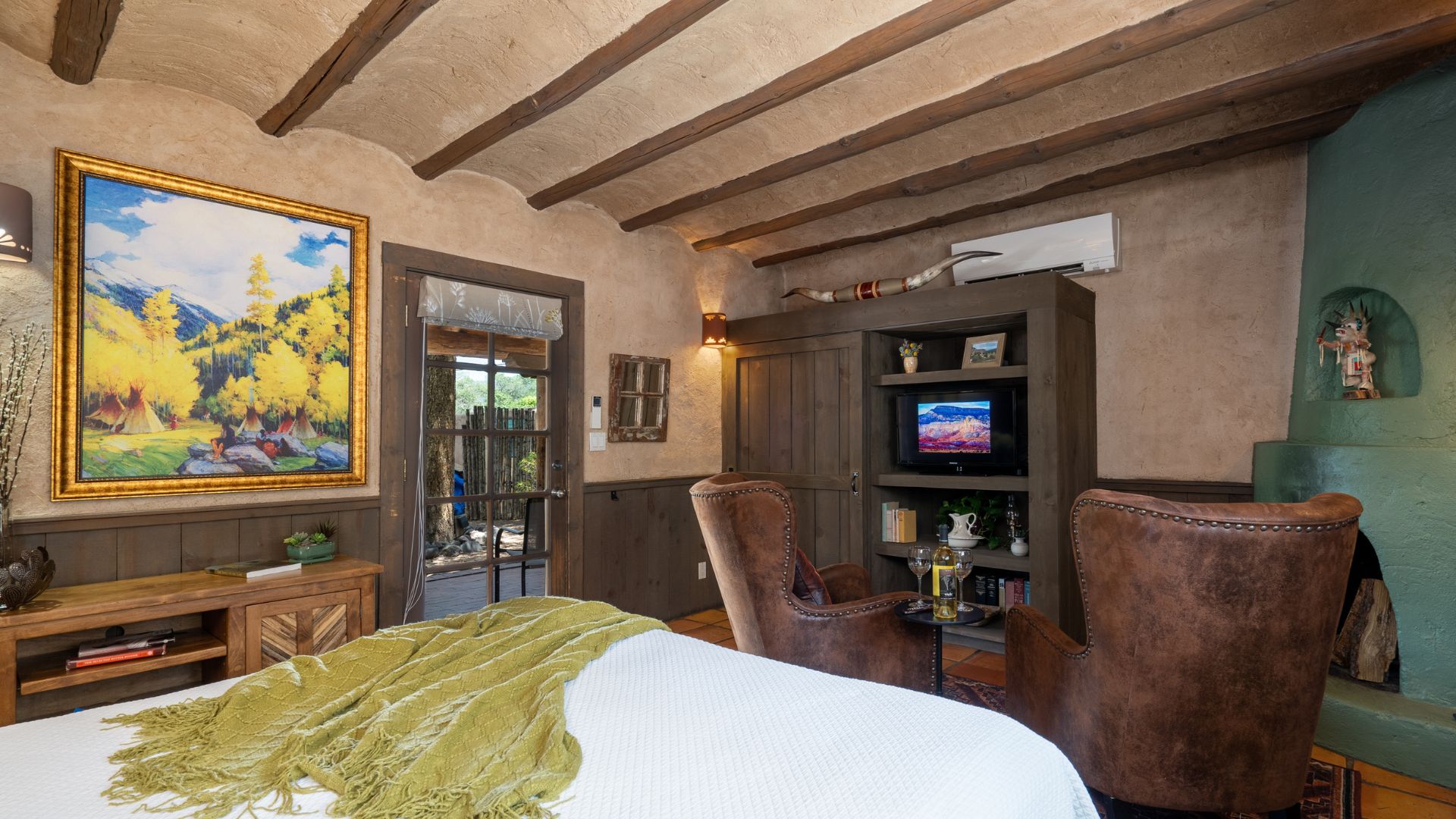 Will Cather guest room with wood ceiling beams, 2 leather chairs, French door to outside, and cozy bed