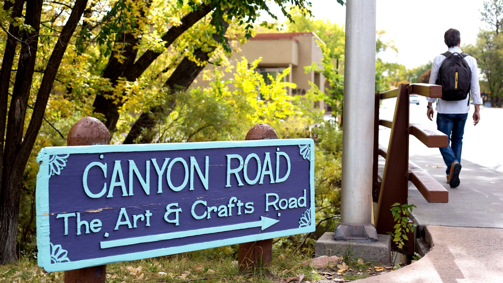 Man with backpack walking by the sign for Canyon Road art district in Santa Fe
