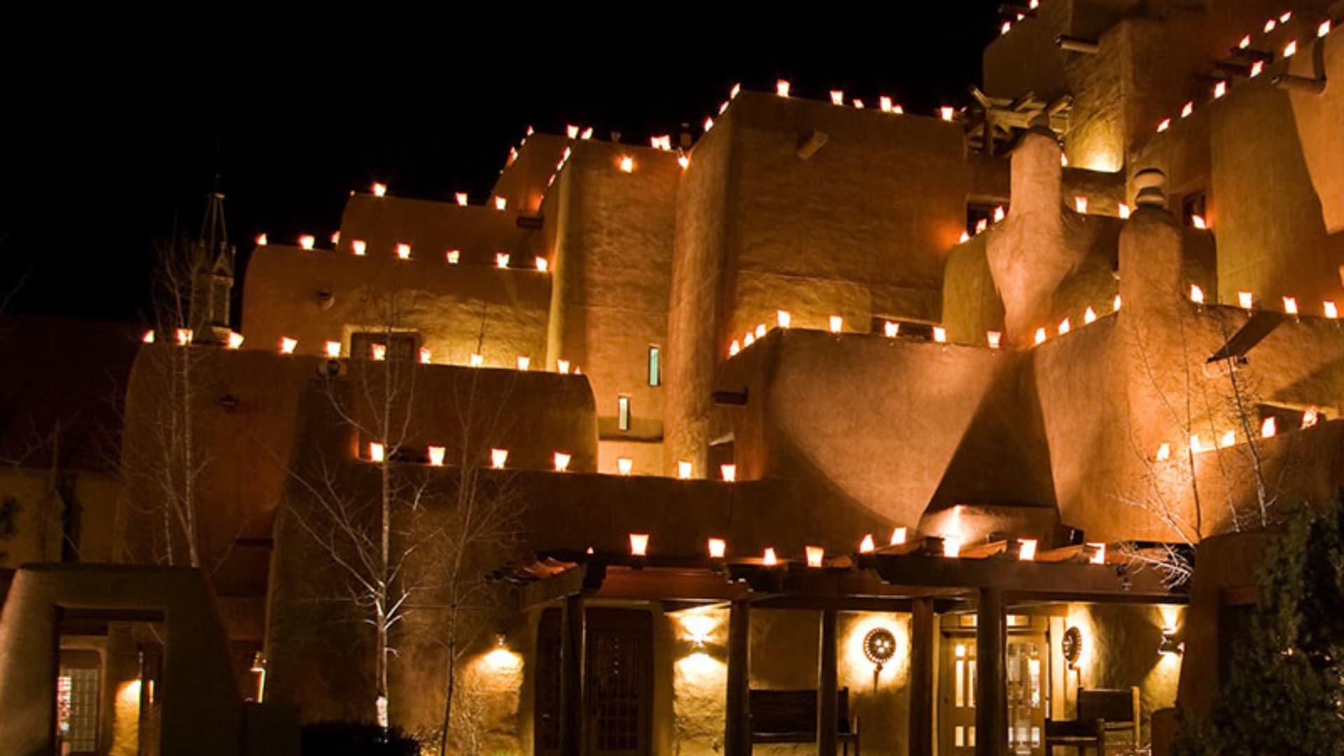 Candlelit farolitos lined on a traditional Santa Fe building at Christmastime