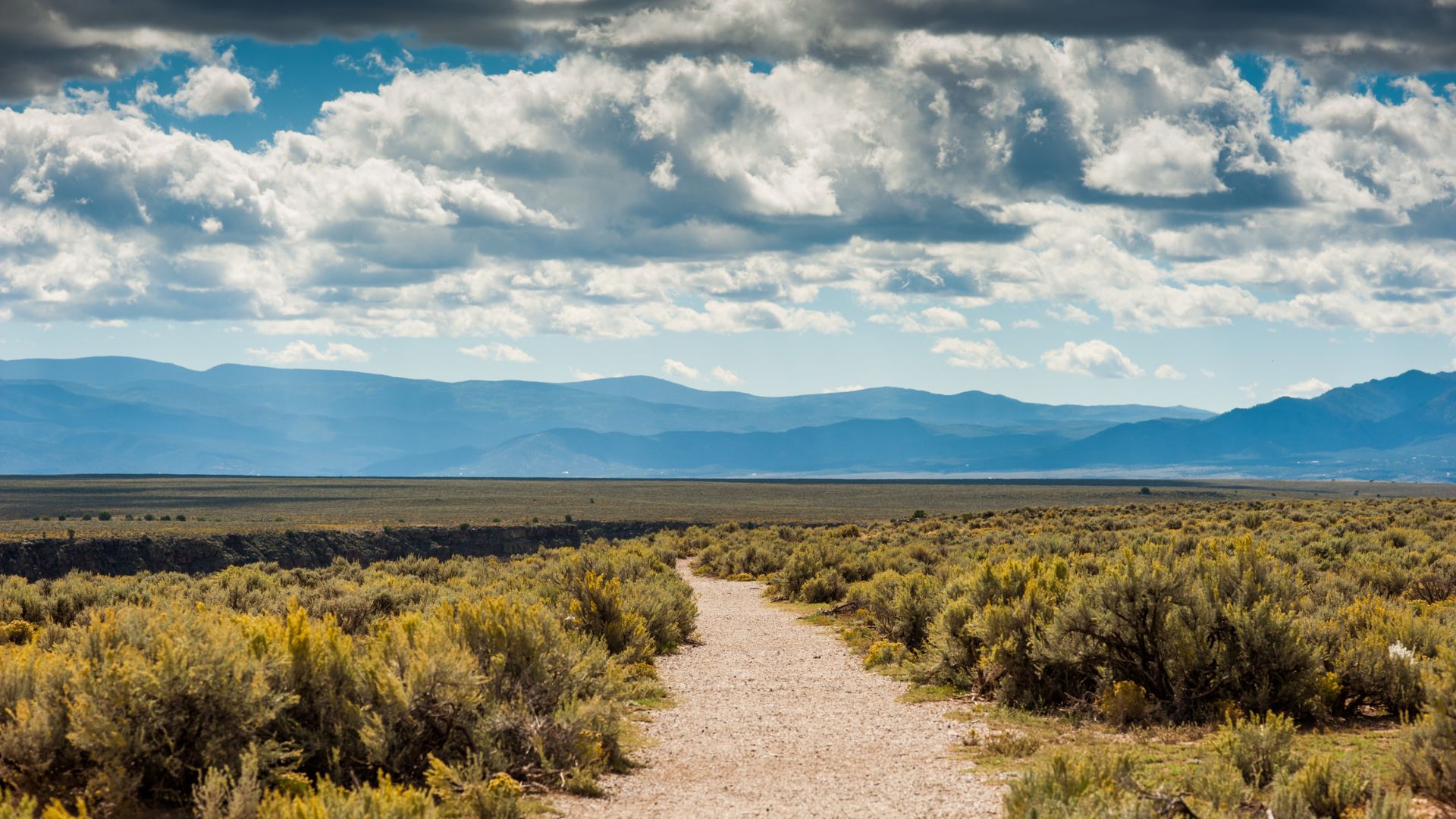 Rural road to Taos with New Mexico mountains in the distance.