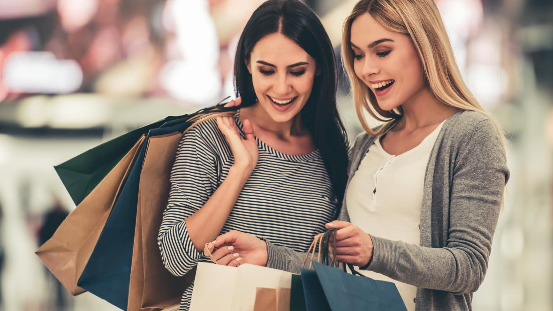 Two girls smiling and holding lots of shopping bags