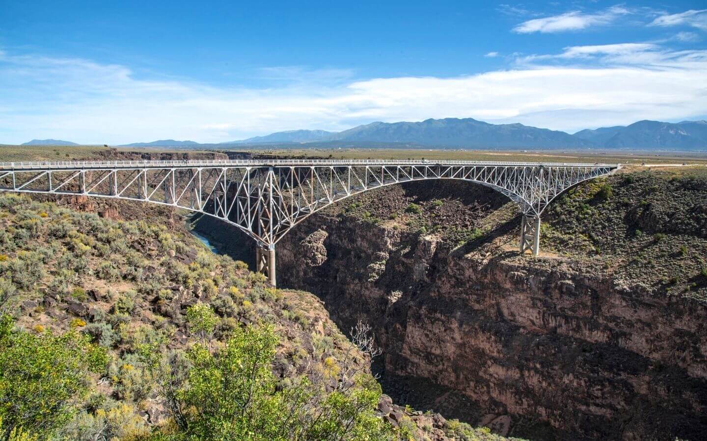 Stunning bridge over two mountains on the way to taos nm amidst blue skies