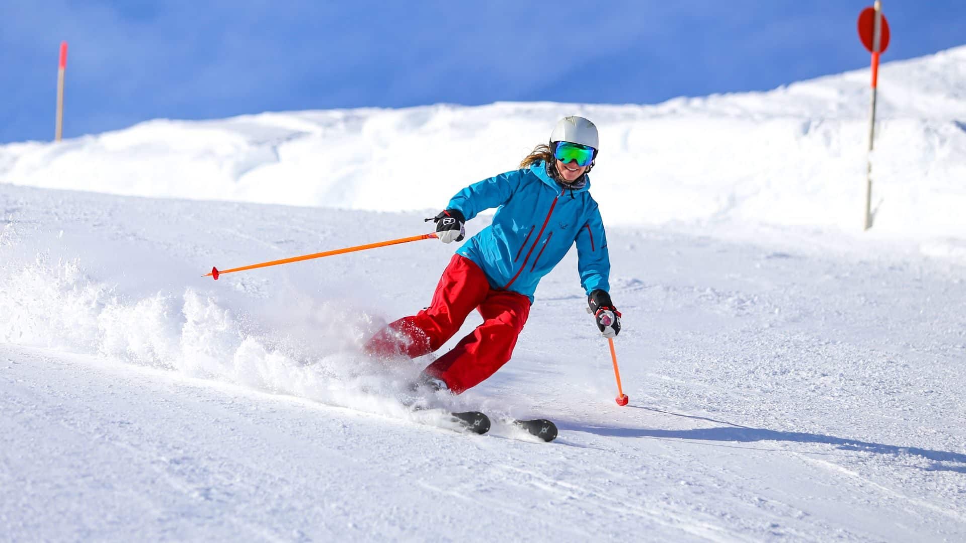 Woman in red downhill skiing surrounded by white snow