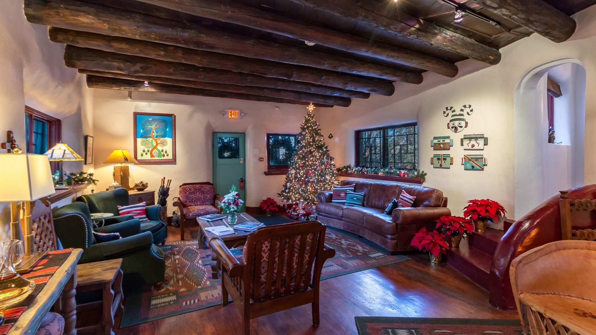 Common living area at The Bear with wood floors and beams all decorated for the holidays with a lit Christmas tree in the corner