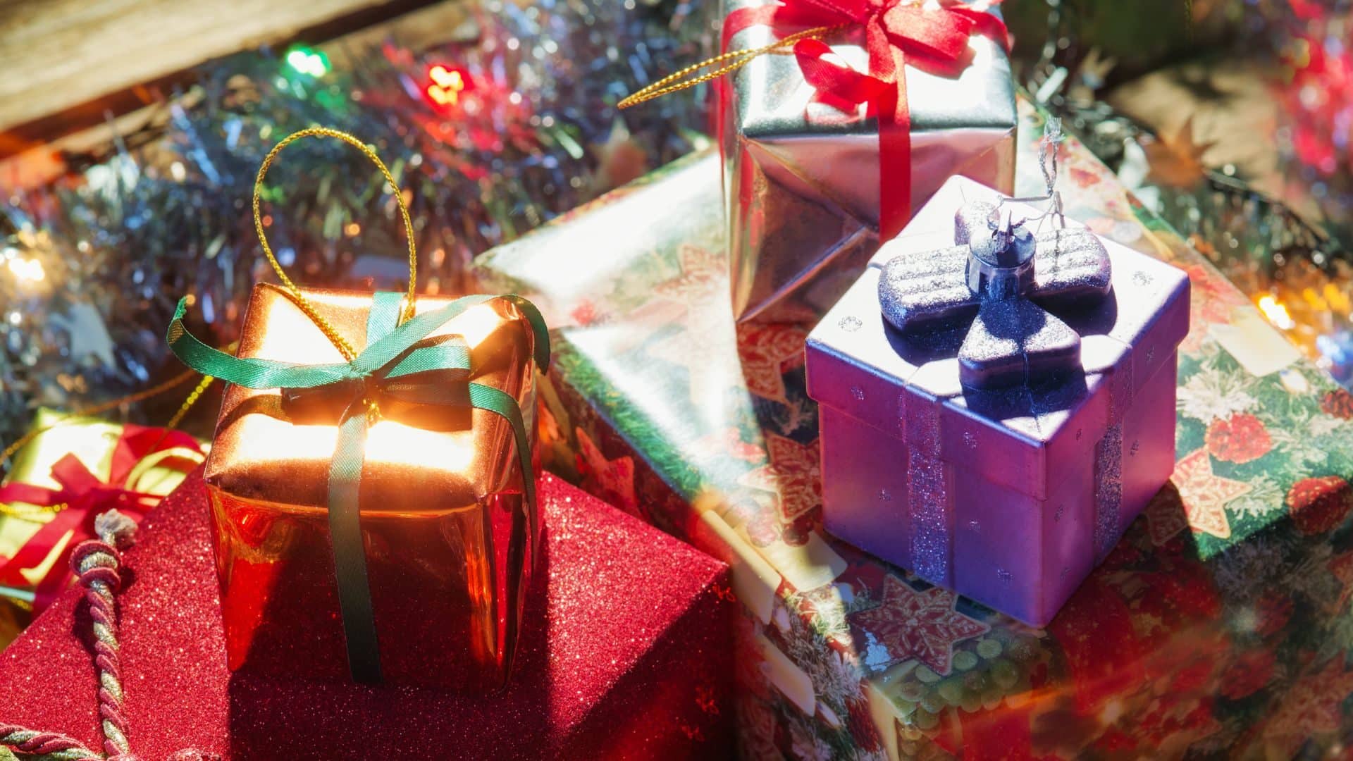 Pile of shimmery colorful Christmas presents with different colored bows.