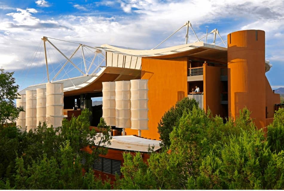 Large orange building with sail-like roof set among Ponderosa Pine trees.