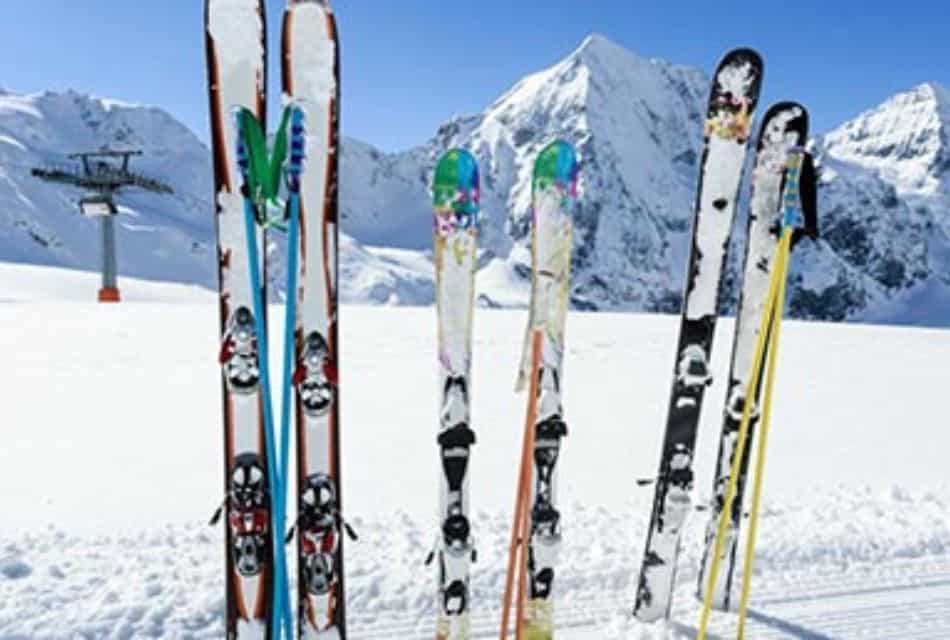 Three sets of colorful skis and poles jut up from deep snow on mountain.
