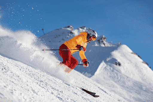 Downhill skier in bright clothng with snow flying behind|Two people snowshoeing with ski poles on trail through woods with large everegreen trees